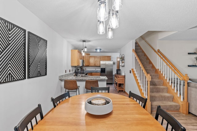 1297 124th Ave NE, Blaine, MN 55434 - dining room featuring stairs, light wood-type flooring, and a textured ceiling