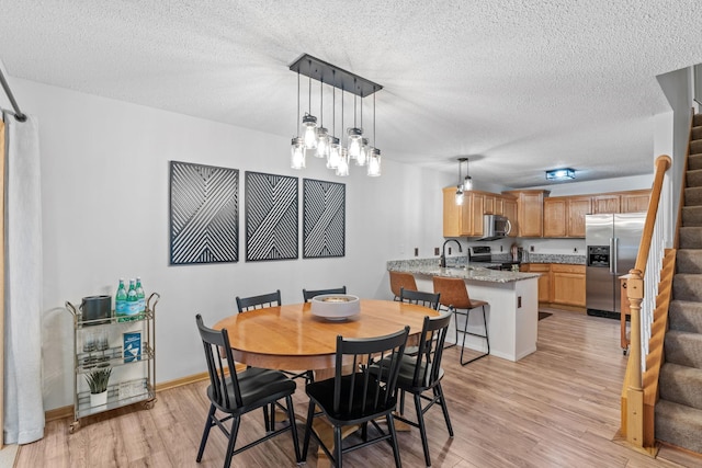 1297 124th Ave NE, Blaine, MN 55434 - dining area featuring stairway, light wood-type flooring, and a textured ceiling