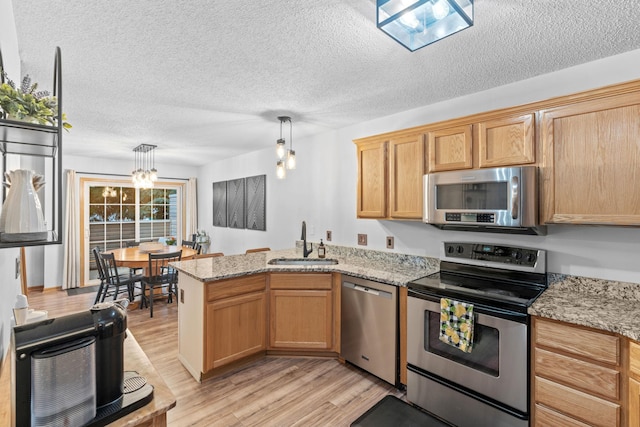 1297 124th Ave NE, Blaine, MN 55434 - kitchen featuring stainless steel appliances, a peninsula, light wood finished floors, a textured ceiling, and hanging light fixtures