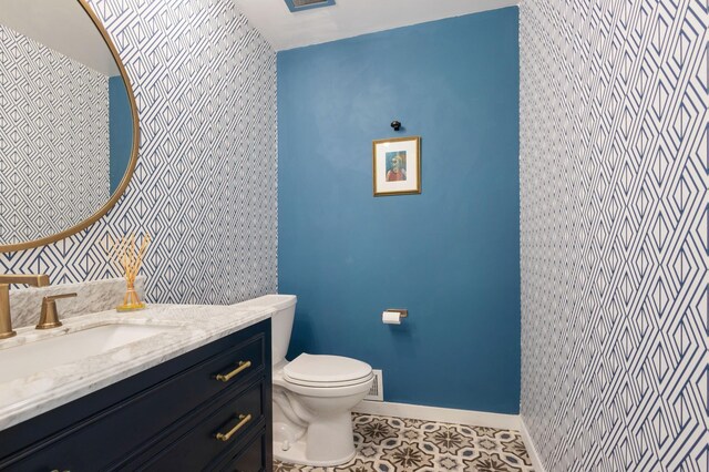 18101 Woolman Dr, Minnetonka, MN 55345 - half bathroom featuring toilet, baseboards, vanity, tile patterned floors, and wallpapered walls