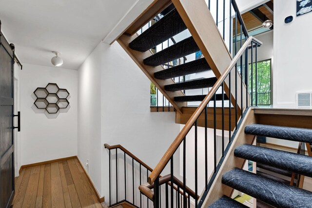 18101 Woolman Dr, Minnetonka, MN 55345 - stairs with hardwood / wood-style flooring, a barn door, and baseboards