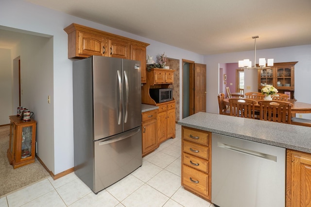 176 Westchester Dr NW, Rochester, MN 55901 - kitchen with appliances with stainless steel finishes, a chandelier, brown cabinetry, light tile patterned floors, and decorative light fixtures