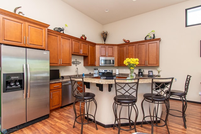 4110 Clubhouse Dr S, Fargo, ND 58104 - kitchen featuring appliances with stainless steel finishes, a center island, a breakfast bar area, and brown cabinetry