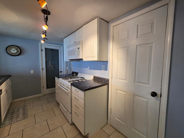 337 Lake Ave N, Spicer, MN 56288 - kitchen featuring white appliances, dark countertops, light tile patterned flooring, white cabinetry, and baseboards