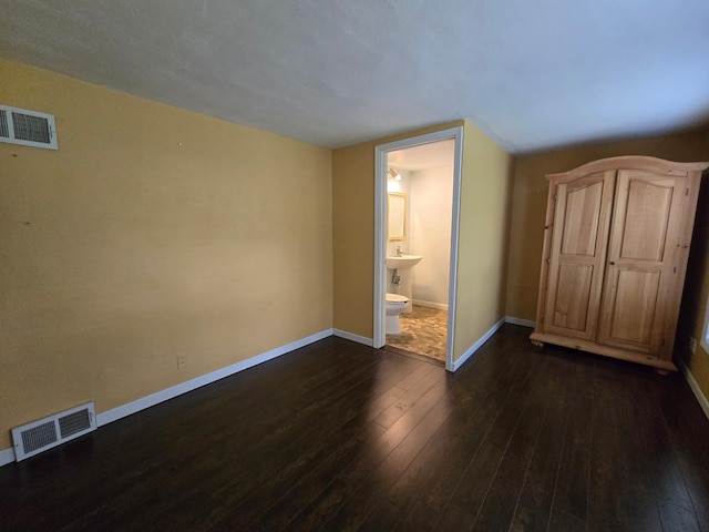 337 Lake Ave N, Spicer, MN 56288 - unfurnished bedroom featuring dark wood-style flooring, baseboards, and connected bathroom
