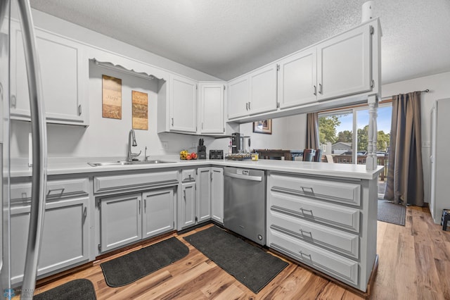 805 7th St NE, Dilworth, MN 56529 - kitchen with a sink, stainless steel dishwasher, light wood-style flooring, a textured ceiling, and light countertops
