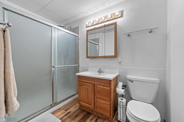 805 7th St NE, Dilworth, MN 56529 - bathroom with vanity, a stall shower, toilet, wood finished floors, and a paneled ceiling