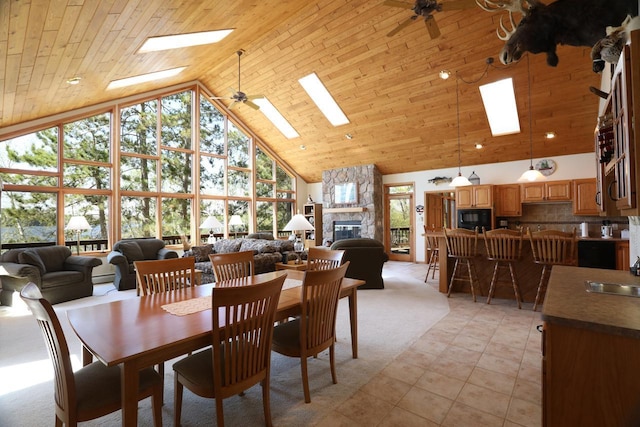 1880 Everett Rd S, Greenwood Twp, MN 55790 - dining area featuring high vaulted ceiling, a ceiling fan, a skylight, a stone fireplace, and light tile patterned floors