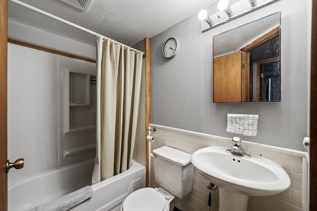 4017 Fordham Dr NE, Saint Anthony, MN 55421 - bathroom with tile walls, shower / bathtub combination with curtain, toilet, a sink, and wainscoting