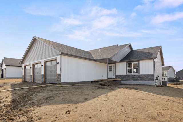 872 Watertown Ave, Delano, MN 55328 - view of front facade with stone siding, an attached garage, a shingled roof, and cooling unit