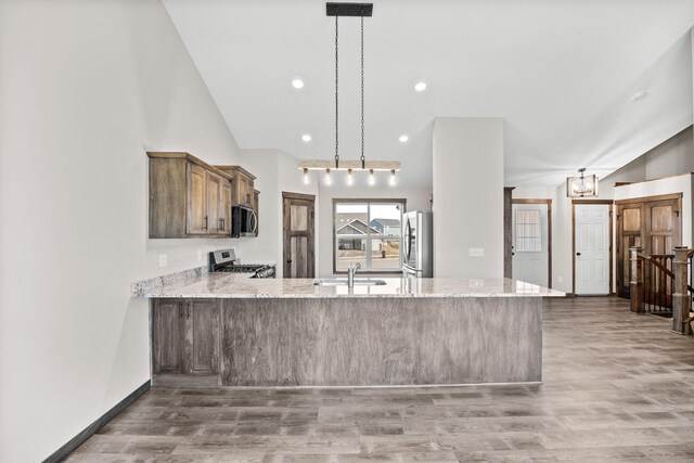 872 Watertown Ave, Delano, MN 55328 - kitchen featuring stainless steel appliances, a sink, a peninsula, wood finished floors, and light stone counters