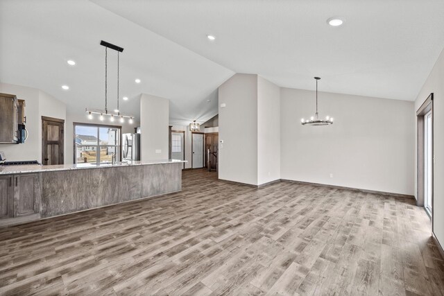 872 Watertown Ave, Delano, MN 55328 - unfurnished living room featuring lofted ceiling, a chandelier, wood finished floors, recessed lighting, and a sink