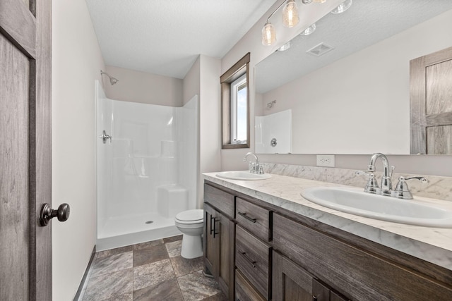 872 Watertown Ave, Delano, MN 55328 - bathroom featuring stone finish flooring, a shower, double vanity, toilet, and a textured ceiling