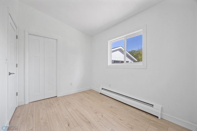 3017 8th St N, Fargo, ND 58102 - unfurnished bedroom with a baseboard radiator, light wood-style floors, baseboards, and a closet