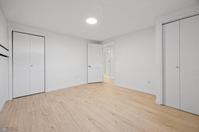 3017 8th St N, Fargo, ND 58102 - unfurnished bedroom featuring light wood-style floors, multiple closets, and baseboards