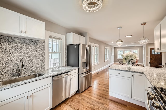 4245 11th Ave S, Minneapolis, MN 55407 - kitchen with stainless steel appliances, a sink, white cabinetry, light wood-style floors, and backsplash