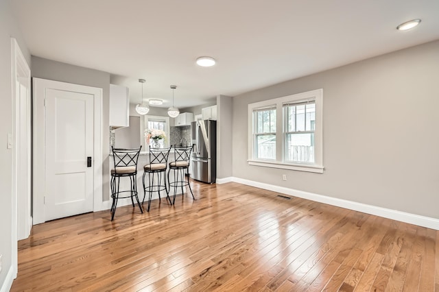 4245 11th Ave S, Minneapolis, MN 55407 - kitchen featuring stainless steel fridge, white cabinetry, a breakfast bar area, light wood-style floors, and a peninsula