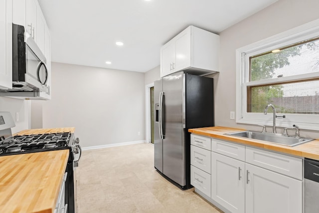 719 9th St E, Glencoe, MN 55336 - kitchen with butcher block countertops, stainless steel appliances, a sink, white cabinetry, and recessed lighting