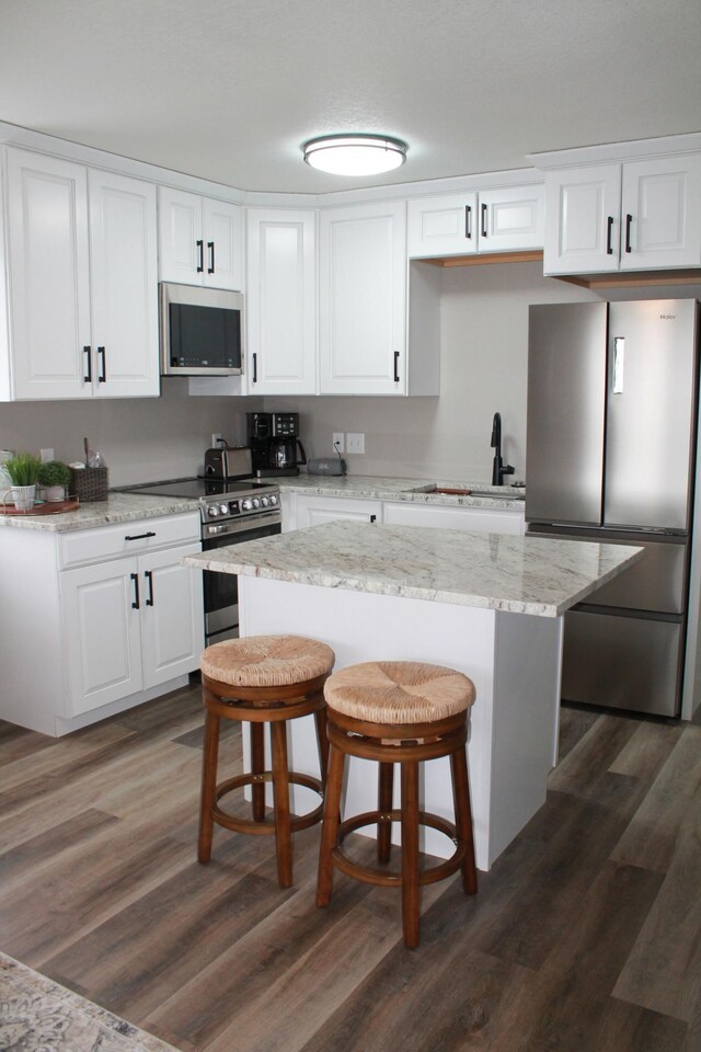 600 Main St W Unit 206, Wabasha, MN 55981 - kitchen featuring appliances with stainless steel finishes, a sink, dark wood-type flooring, white cabinetry, and a breakfast bar