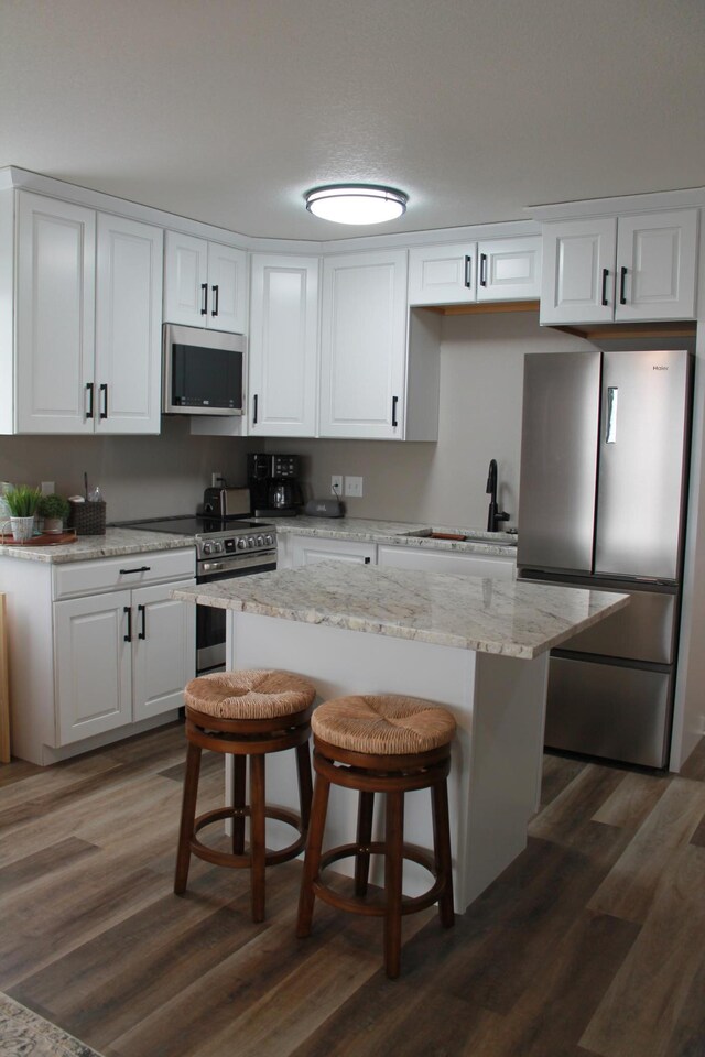 600 Main St W Unit 206, Wabasha, MN 55981 - kitchen with appliances with stainless steel finishes, white cabinets, dark wood finished floors, a sink, and a breakfast bar area