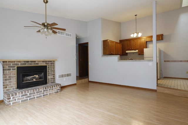16477 Five Hawks Ave SE, Prior Lake, MN 55372 - unfurnished living room with light wood-type flooring, a ceiling fan, baseboards, high vaulted ceiling, and a brick fireplace