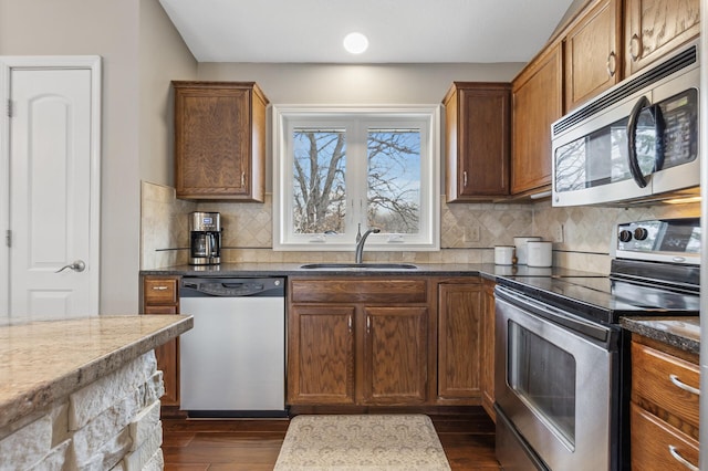 3664 Canary Way, Eagan, MN 55123 - kitchen featuring appliances with stainless steel finishes, a sink, dark wood-type flooring, backsplash, and brown cabinets