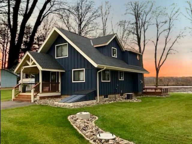 2051 Pine Knoll Rd, Knife Lake Twp, MN 55051 - back of house at dusk with board and batten siding, a lawn, a shingled roof, and covered porch
