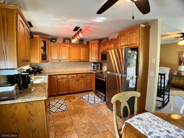 204 10th St N, Sartell, MN 56377 - kitchen with appliances with stainless steel finishes, ceiling fan, brown cabinets, stone tile flooring, and decorative backsplash