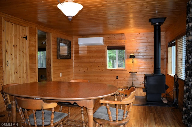 48080 218th Pl, Mcgregor, MN 55760 - dining room featuring a wood stove, a wall mounted air conditioner, wood ceiling, wooden walls, and wood finished floors