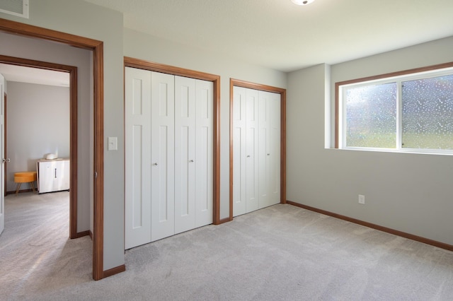 1004 7th Ave NW, Kasson, MN 55944 - unfurnished bedroom with light carpet, two closets, and baseboards
