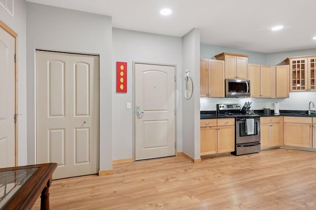4132 Vernon Ave S Unit A103, Saint Louis Park, MN 55416 - kitchen with appliances with stainless steel finishes, light brown cabinets, dark countertops, decorative backsplash, and light wood-style flooring