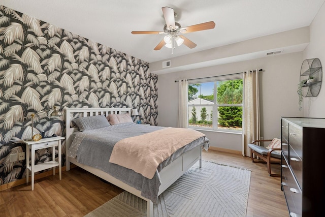 4132 Vernon Ave S Unit A103, Saint Louis Park, MN 55416 - bedroom featuring light wood finished floors, an accent wall, ceiling fan, baseboards, and wallpapered walls