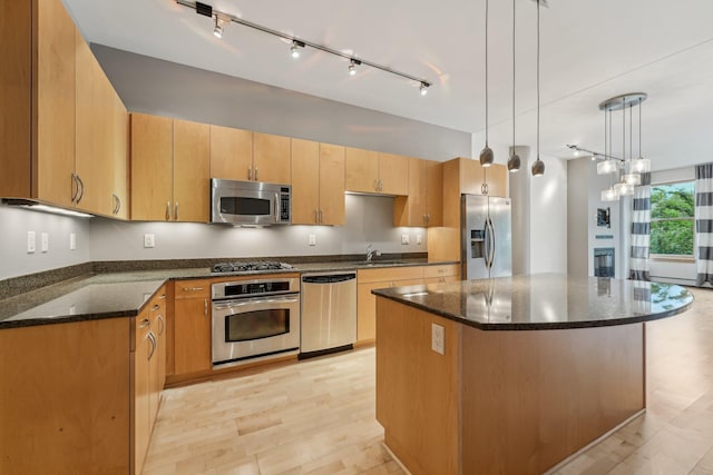 401 2nd St N Unit 220, Minneapolis, MN 55401 - kitchen with stainless steel appliances, dark stone counters, a center island, hanging light fixtures, and light wood-type flooring