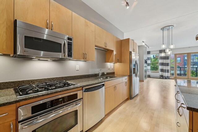 401 2nd St N Unit 220, Minneapolis, MN 55401 - kitchen with appliances with stainless steel finishes, a sink, light wood-style flooring, pendant lighting, and dark stone countertops