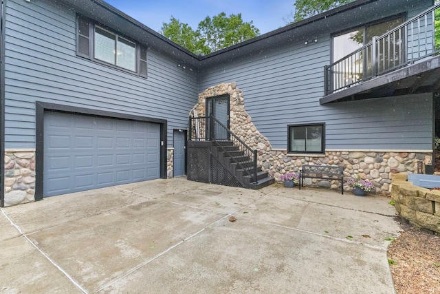 1680 Bluebird Ln, Mound, MN 55364 - view of front of house featuring stone siding, a balcony, a garage, and driveway