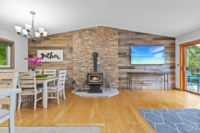 1680 Bluebird Ln, Mound, MN 55364 - dining room featuring wood walls, hardwood / wood-style flooring, vaulted ceiling, a wood stove, and a chandelier