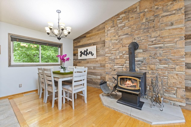 1680 Bluebird Ln, Mound, MN 55364 - dining room featuring a wood stove, a chandelier, vaulted ceiling, wood finished floors, and baseboards