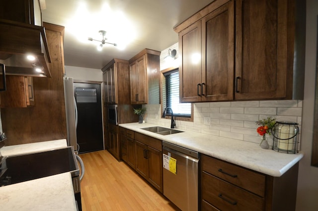 415 Hubbard Ave N, Litchfield, MN 55355 - kitchen with appliances with stainless steel finishes, a sink, light wood-style flooring, backsplash, and light countertops
