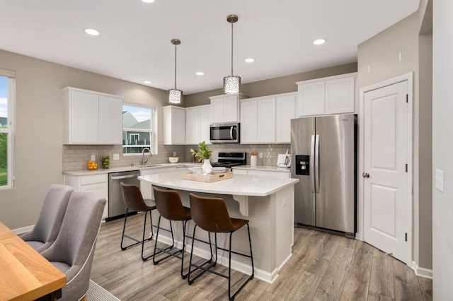 5010 Sandpebble Ln, Woodbury, MN 55129 - kitchen featuring stainless steel appliances, a sink, a kitchen island, tasteful backsplash, and a kitchen breakfast bar