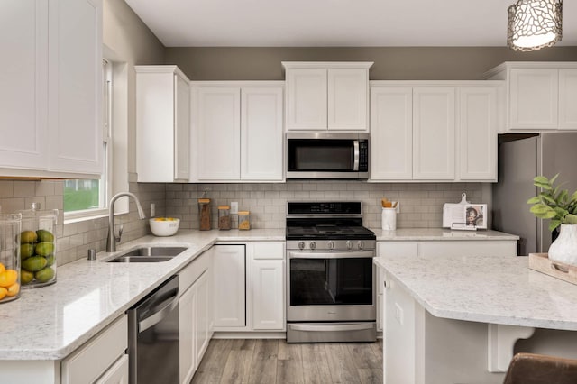 5010 Sandpebble Ln, Woodbury, MN 55129 - kitchen featuring appliances with stainless steel finishes, a sink, white cabinetry, and light wood finished floors