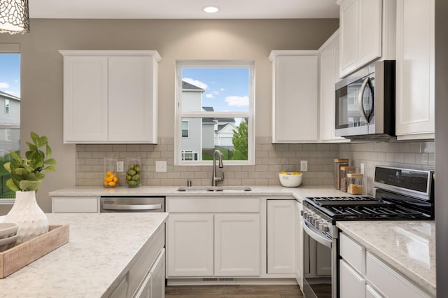 5010 Sandpebble Ln, Woodbury, MN 55129 - kitchen with appliances with stainless steel finishes, a sink, white cabinets, recessed lighting, and healthy amount of natural light