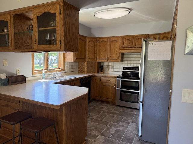 507 Pine Ridge Ter, River Falls, WI 54022 - kitchen with appliances with stainless steel finishes, a peninsula, brown cabinetry, decorative backsplash, and glass insert cabinets