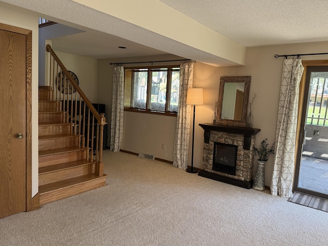 507 Pine Ridge Ter, River Falls, WI 54022 - unfurnished living room featuring carpet flooring, stairway, a stone fireplace, a textured ceiling, and baseboards