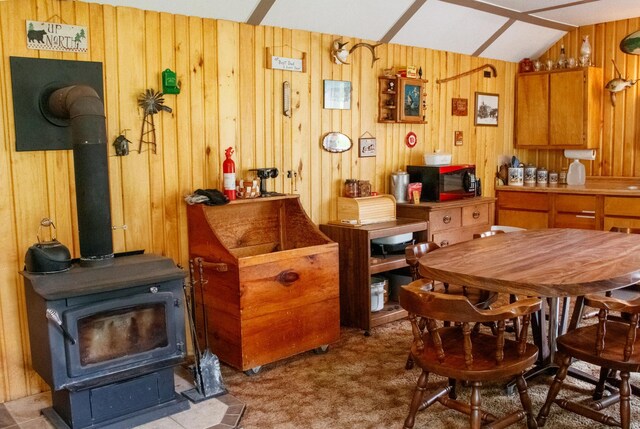 11005 320th St, Clover Twp, MN 56470 - carpeted dining area with a wood stove, wooden walls, and lofted ceiling