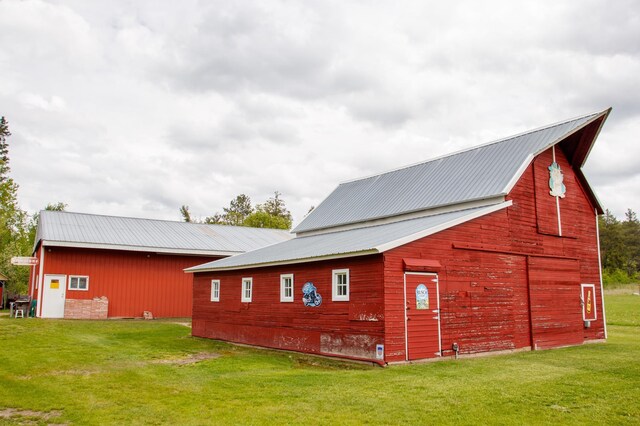 11005 320th St, Clover Twp, MN 56470 - view of property exterior with a barn, metal roof, a lawn, and an outdoor structure