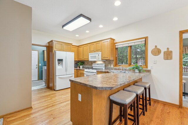 307 Lincoln Dr SE, Saint Michael, MN 55376 - kitchen featuring white appliances, a sink, light wood-type flooring, a peninsula, and tasteful backsplash