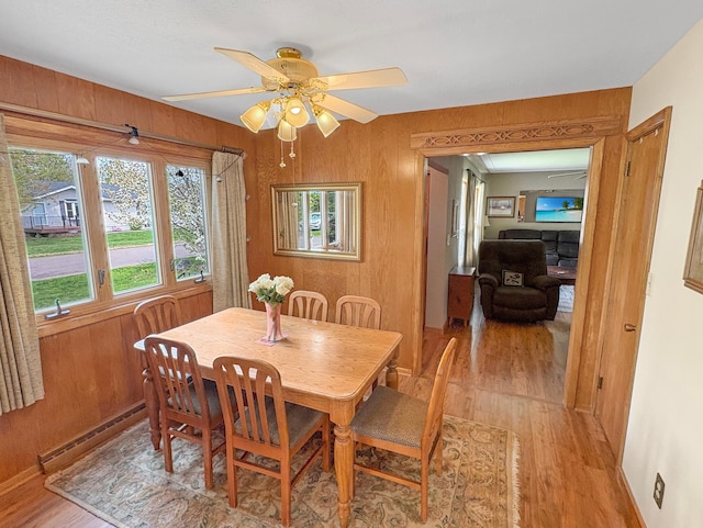602 26th St, Scanlon, MN 55720 - dining room with light wood-type flooring, a ceiling fan, a baseboard radiator, and wood walls