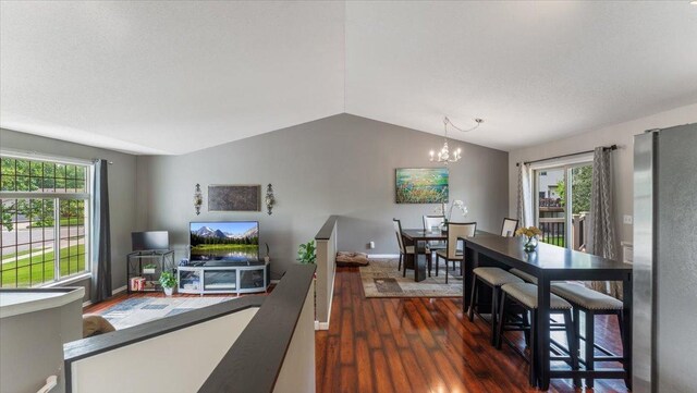 13590 Jesse St, Becker, MN 55308 - dining space featuring wood finished floors, vaulted ceiling, a chandelier, and baseboards