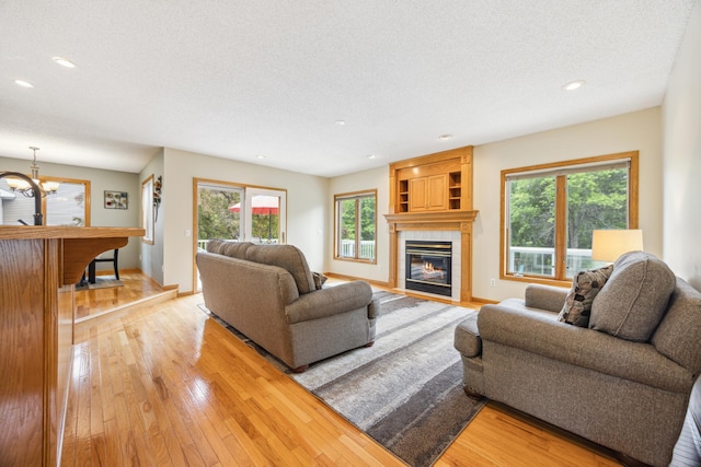 582 139th Ln NW, Andover, MN 55304 - living room featuring light wood-style floors, a textured ceiling, a tile fireplace, recessed lighting, and a chandelier
