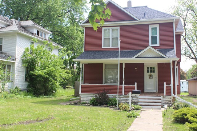 835 Park St, Fairmont, MN 56031 - american foursquare style home featuring a shingled roof, a front lawn, and covered porch